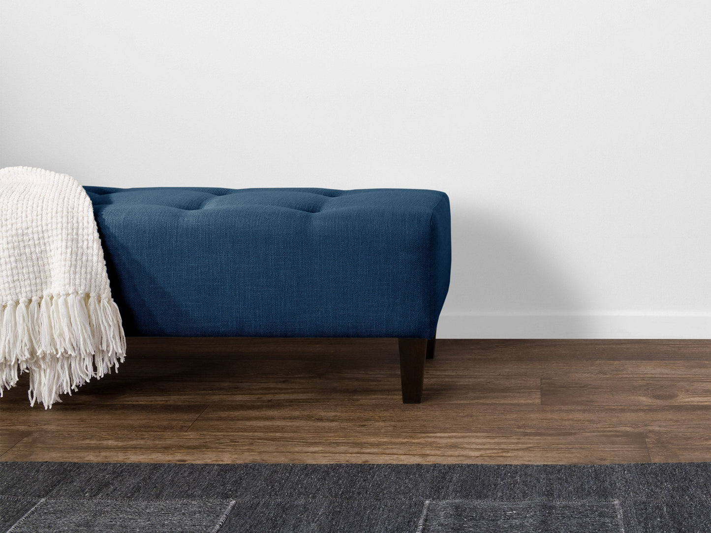 Navy blue accent bench with plush velvet upholstery, sleek wooden legs, and tufted seat cushion.