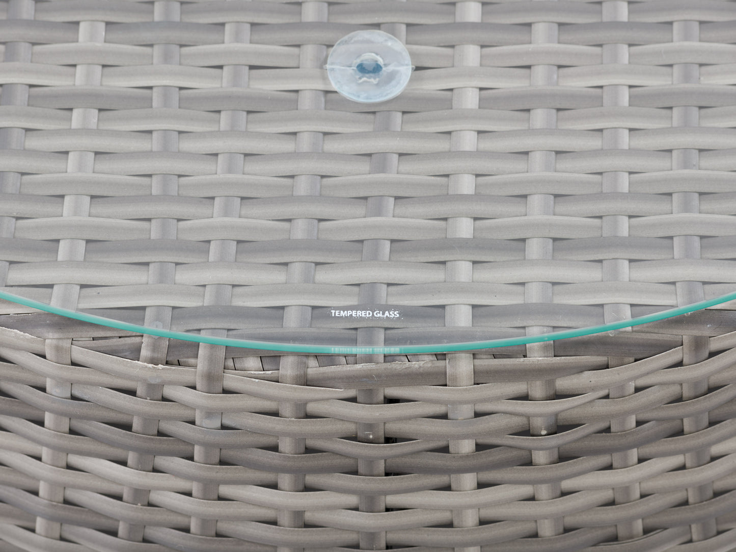 Wicker coffee table with a round glass top, natural brown woven rattan base, and sturdy construction, ideal for outdoor patio settings.