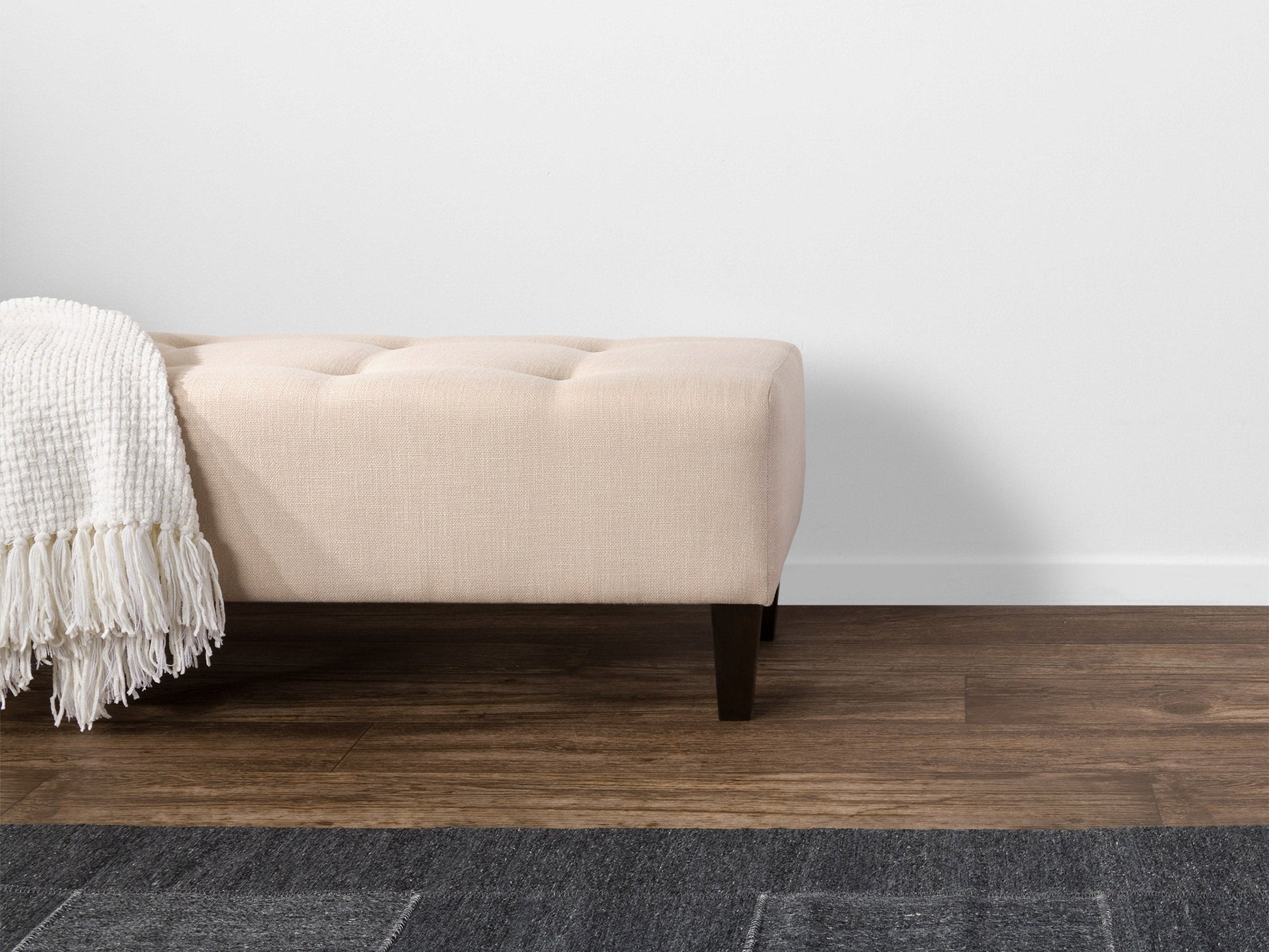 Cream accent bench with wooden legs, upholstered fabric, and tufted seat for living room or hallway decor.