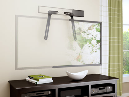 Wall-mounted black soundbar mount with adjustable brackets, holding a sleek soundbar beneath a flat-screen TV on a white wall. Ideal for enhancing home theater audio setup and saving space.