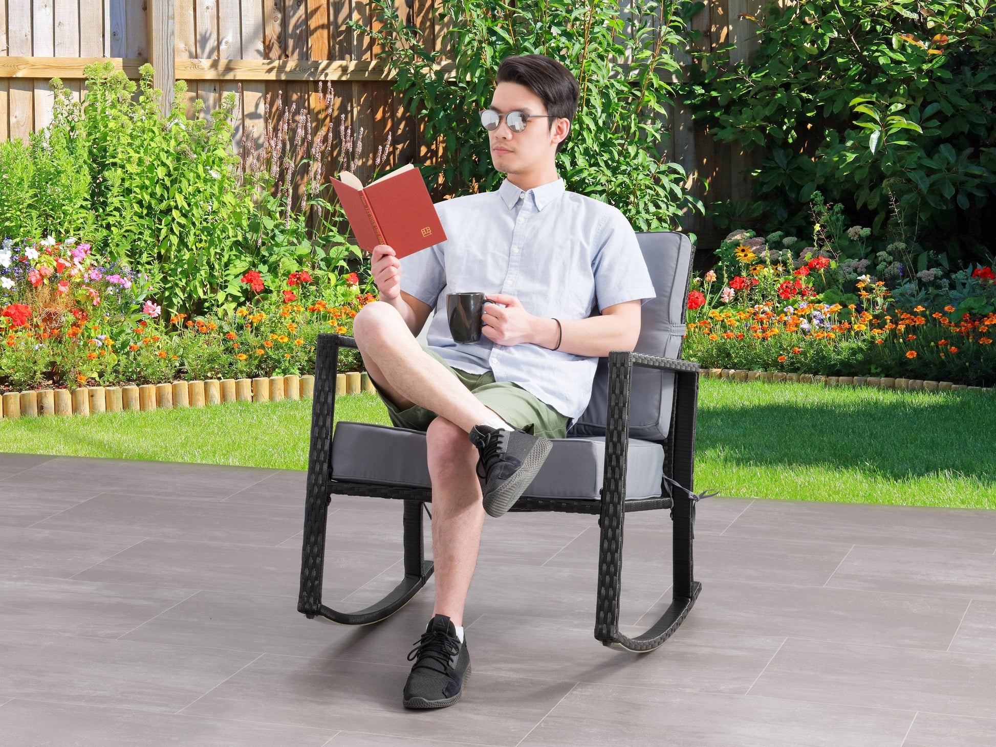 Black and grey wicker outdoor rocking chair with cushioned seat and backrest, perfect for patio relaxation.