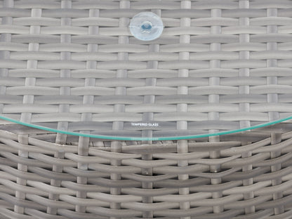 Wicker coffee table with a round glass top, natural brown woven rattan base, and sturdy construction, ideal for outdoor patio settings.
