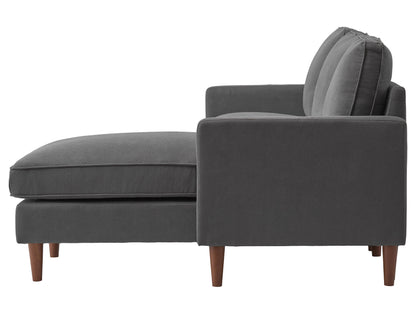Reversible sectional sofa in light gray fabric with tufted cushions, chaise lounge, and wooden legs, perfect for modern living rooms, providing comfort and style with its versatile design and spacious seating.